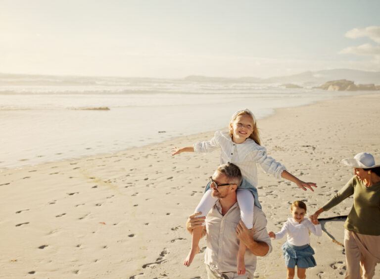 Das Bild zeigt eine lachende Familie am Strand