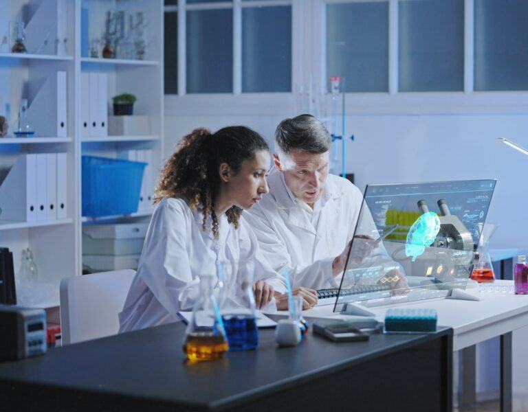 Das Bild zeigt ein Büro mit zwei Ärzten vor einem digitalen Bildschirm